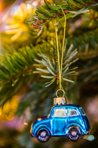 Foto av en julgranskula i form av en blå bil hängande i en julgran